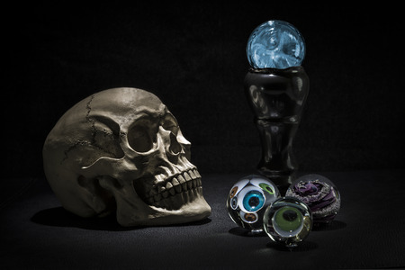 Dark and shadowy human skull in a pool of light. Crystal balls with eyeballs looking outの写真素材