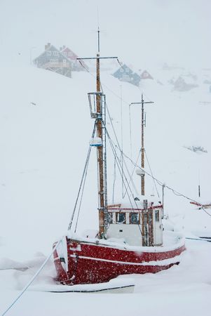 A snowed up red boat being stuck in the iceの写真素材