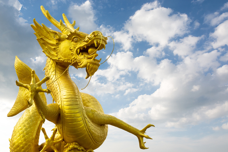 Golden Chinese dragon statue with cloud and blue sky.の写真素材
