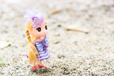 Dolls with Wearing a purple dress Blond hair on the sand.