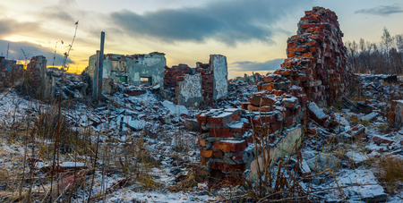 Apocalyptic landscape.The remains of destroyed houses covered with snow at sunsetの写真素材