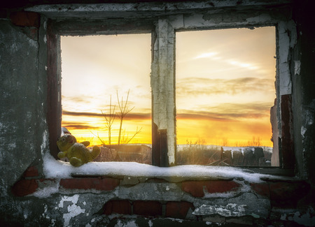 The post-apocalyptic world.The old toy in the window of a ruined house at sunsetの写真素材