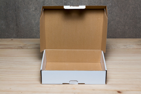 Opened cardboard box on wooden background