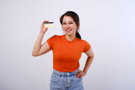 Smiling Asian woman wearing casualÂ shirt holding credit card isolated on white backgroundの写真素材