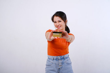 Smiling Asian woman wearing casualÂ shirt holding credit card isolated on white backgroundの写真素材