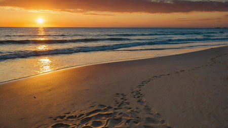 Beautiful sunset on the beach with footprints in the sand and wavesの写真素材
