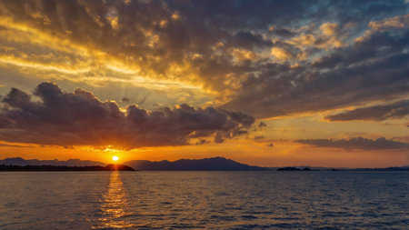 Beautiful sunset over the sea with clouds and mountains on the horizonの写真素材