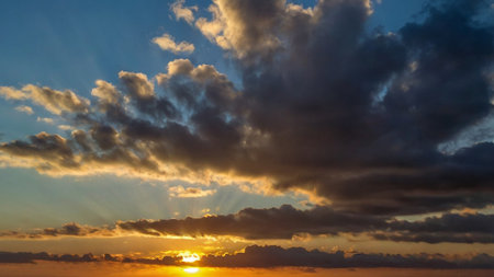 Sunset sky with clouds and sunbeams. Beautiful nature background.