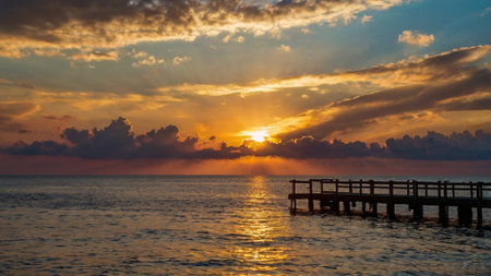 Sunset over the sea with a wooden jetty in the foregroundの写真素材