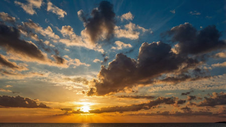 Sunset over the sea with clouds and sunbeams on the horizonの写真素材