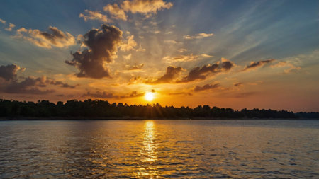 beautiful sunset on the river in summer with clouds and sun raysの写真素材