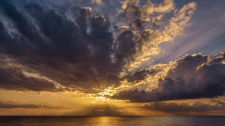 Beautiful sunset on the sea with sun rays and dramatic clouds.の写真素材
