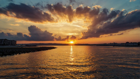 Sunset over the sea with clouds reflected in the water surface.の写真素材