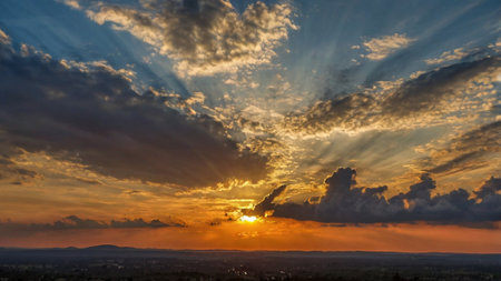 Dramatic sunset over the city with clouds and sun rays.