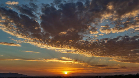 Sunset with clouds in the blue sky and mountain in the backgroundの写真素材