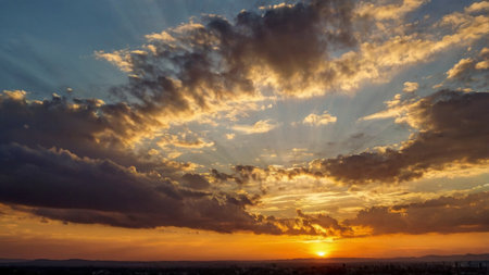 Beautiful sunset over the city. The rays of the sun break through the clouds.の写真素材