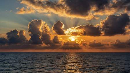 Sunset over the sea with clouds and rays of light shining through the cloudsの写真素材