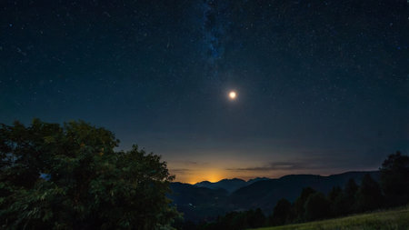 Night sky with stars and the moon. The starry sky over the mountains.