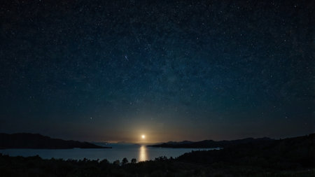 Night sky with stars and milky way over lake. Long exposure.