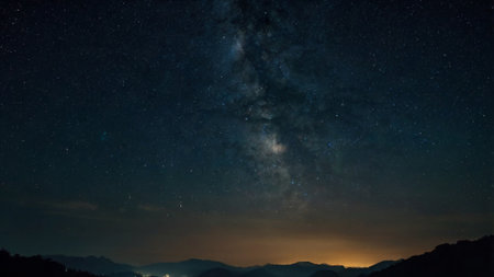 Milky way in the night sky with stars and silhouette of mountains