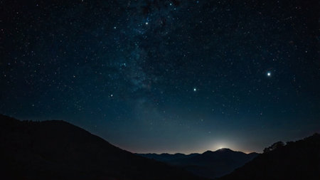Milky way over the mountains at night with stars in the skyの写真素材