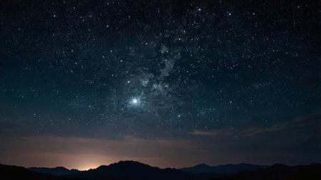 Milky way and stars in the night sky with mountains and cloudsの写真素材