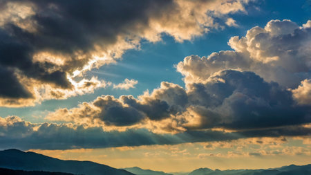 Dramatic sunset sky with clouds and sunbeams over mountainsの写真素材