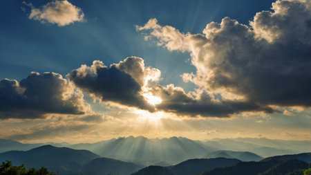 Sunset over the mountains with sun rays passing through the clouds.の写真素材