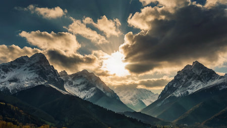 Mountain landscape with snow-capped peaks and clouds at sunsetの写真素材