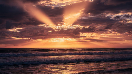 Sunset on the beach with rays of light coming through the clouds