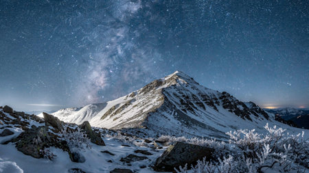 Mountain landscape with starry night sky and milky way over the peak