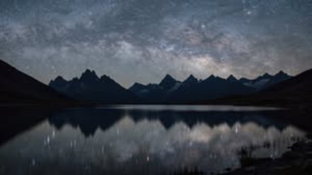 Fantastic starry sky over mountain lake. Panoramic view of the lake in the mountains.