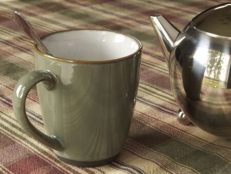 Tea Cup sitting beside a chrome tea pot  の写真素材
