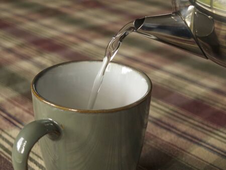 Tea Cup sitting beside a chrome tea pot  の写真素材