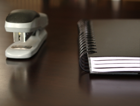 Notepad sitting on a desk with a staplerの写真素材