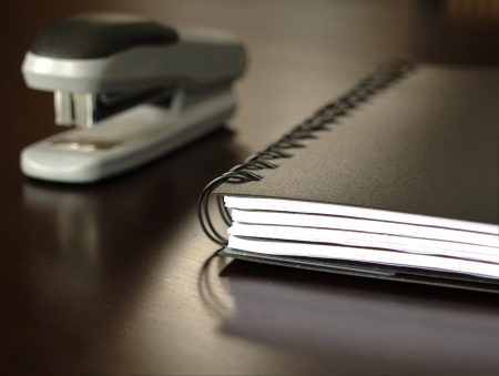Notepad sitting on a desk with a staplerの写真素材
