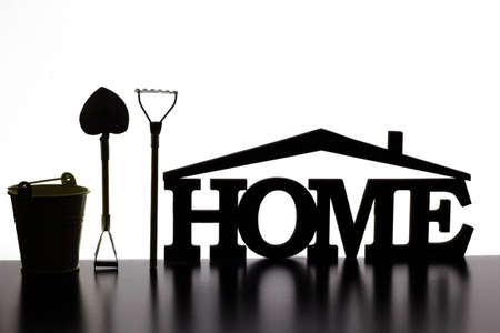The word "home" made of wood, next to a bucket, rake, shovelの写真素材
