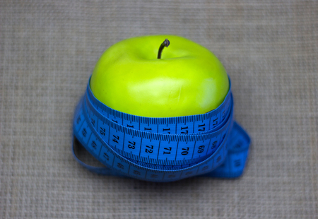 Apple with measuring tape on the background of burlapの写真素材