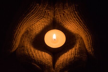 Candle light glowing in woman's hands. Praying, faith, religion concept.の写真素材