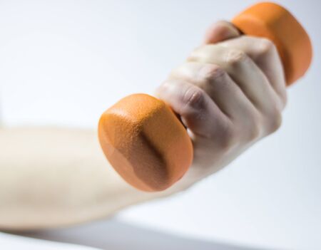 Hand holding an orange dumbbell close upの写真素材