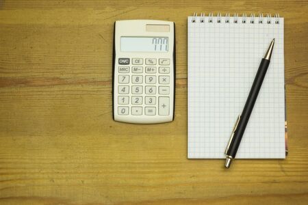 Wooden table at office with calculator, pen and paper. Background with copy space.の写真素材