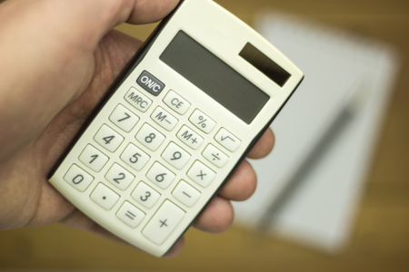 Man using calculator to count income and outcomeの写真素材