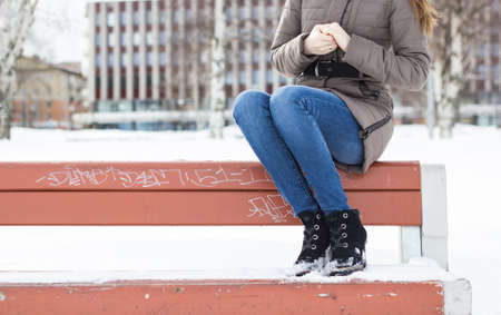 Beautiful girl sitting on a bench on a city backgroundの写真素材