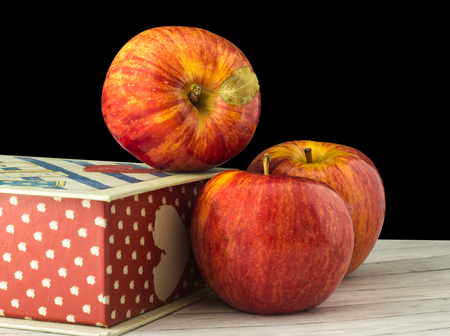 Fruits of a red apple with leaves near the gift boxの写真素材