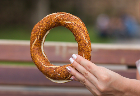 Girl holding a Turkish bagel (simit) in her hand, close-up