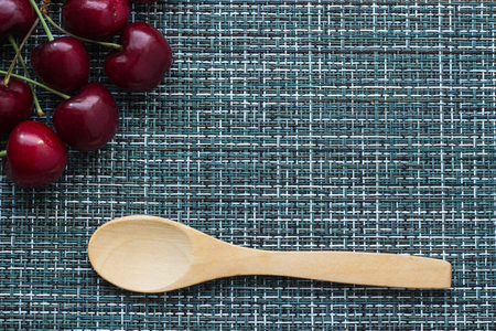Ripe cherries on a wicker background and a wooden spoon, close-upの写真素材