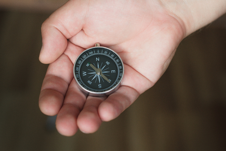Young man holds a compass in his handの写真素材