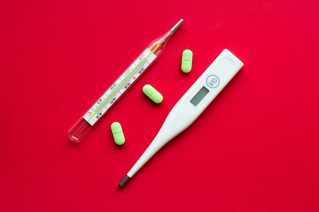Mercury and electronic thermometer on a red backgroundの写真素材