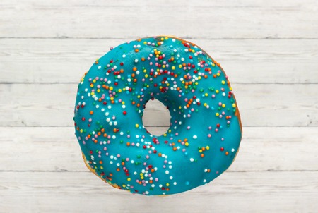 Donut blue with sprinkles isolated on wooden background, close-upの写真素材