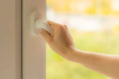 Female hand opens the window to the street, close-upの写真素材
